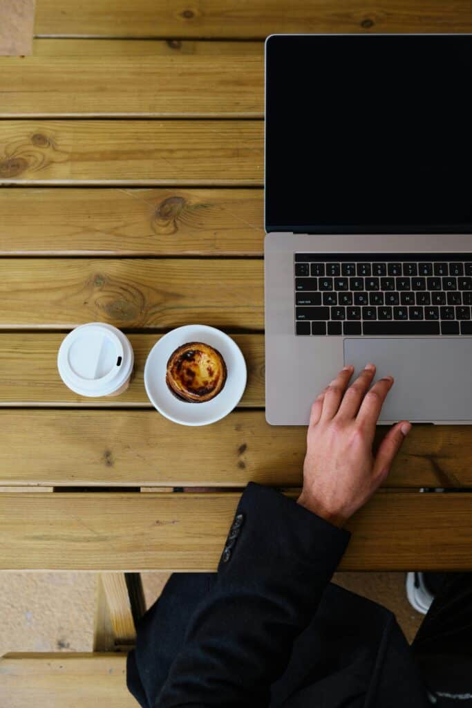 Overhead view of a person working at a laptop with coffee