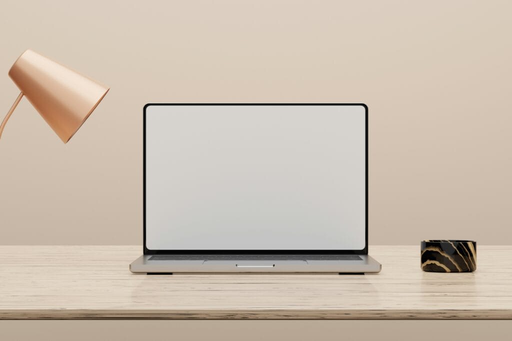 A laptop on a clean desk beside a warm desk lamp