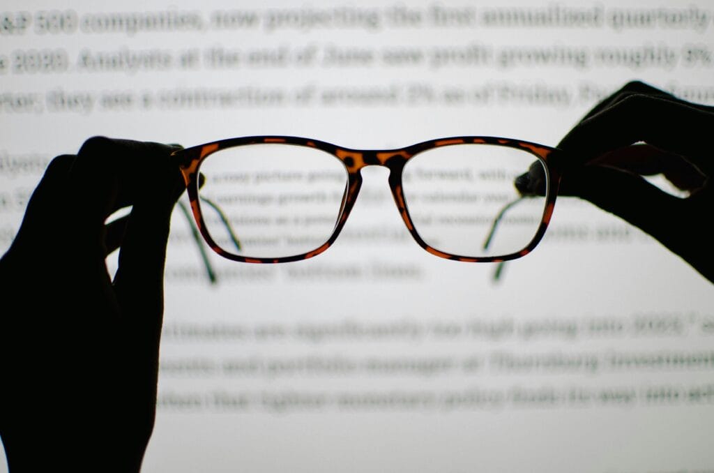 Reading glasses held up against text on a screen